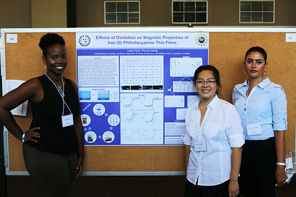 three students standing next to their poster presentation