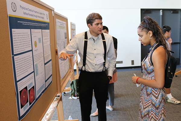 student researcher explaining his research to another student