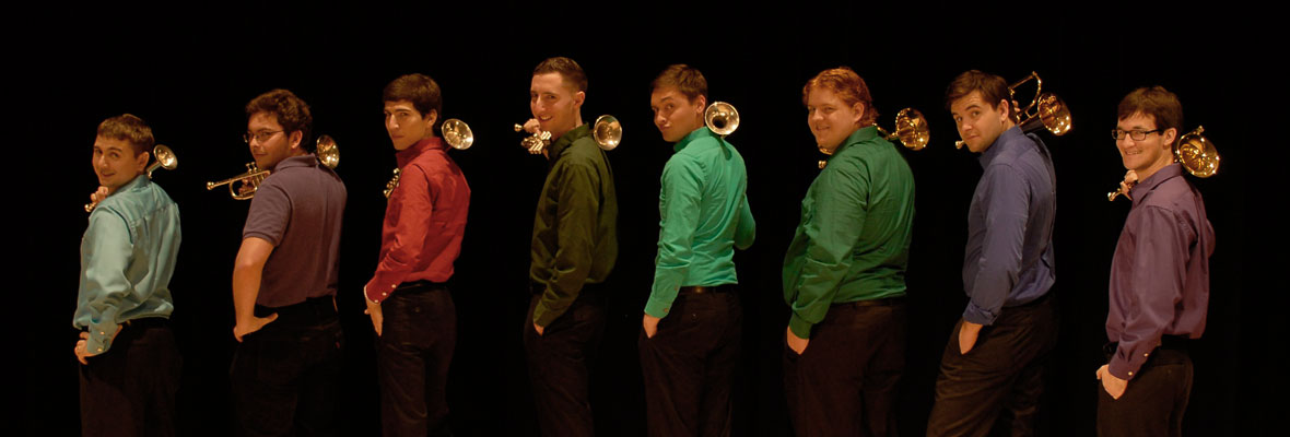 Brass players in multi-colored shirts looking over their shoulders.